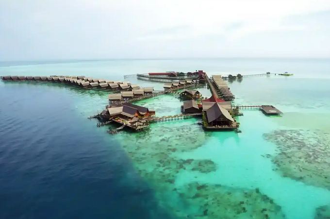 Aerial view of the over-water chalets of Kapalai Resort on a turquoise reef