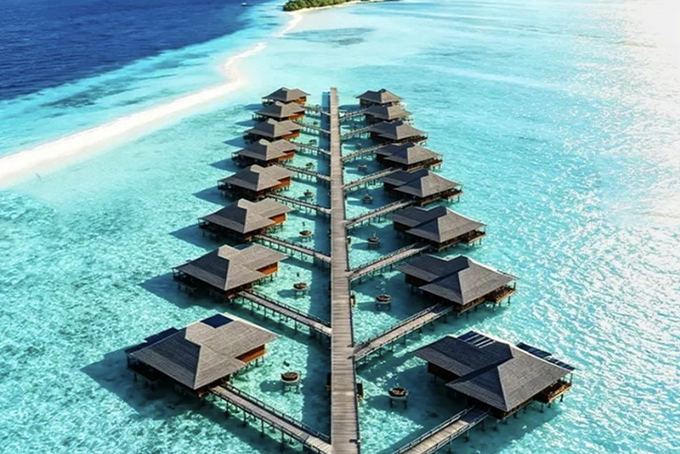 Aerial view of two rows of water villas along a jetty at Mataking Resort