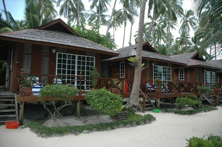 Timber stand-alone chalets with verandas among coconut palms at Sipadan-Mabul Resort